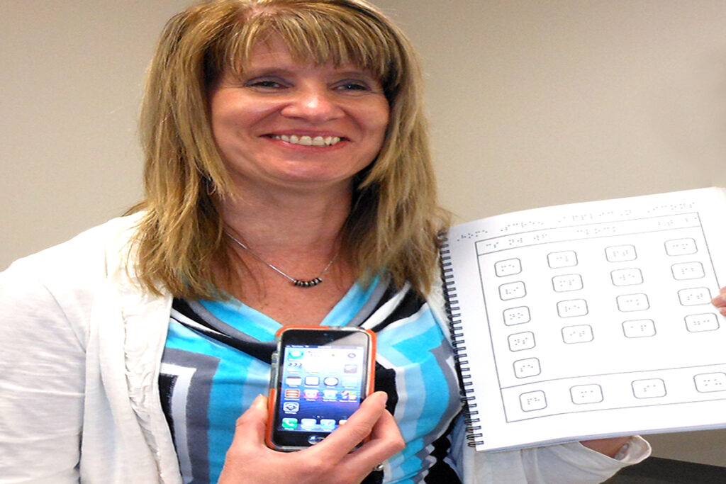 Picture of a woman with vision loss with a smart phone and a braille book