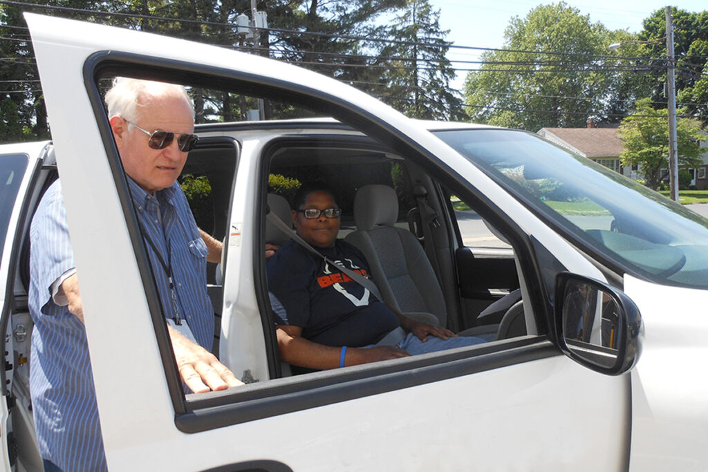 Picture of a client getting into an agency van with help from a driver