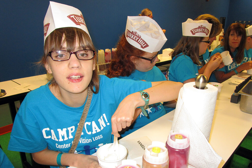 Photo of a young girl making her own ice cream sundae as part of our Camp I CAN! program for kids