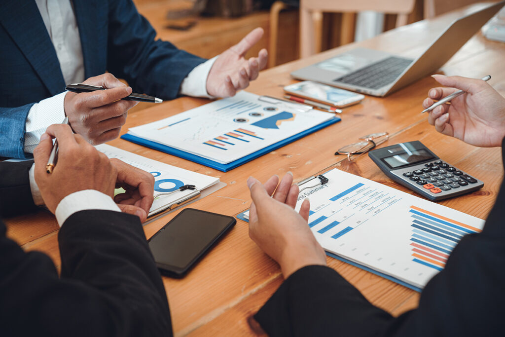 A photo of businesspeople seated at a table and reviewing financial charts