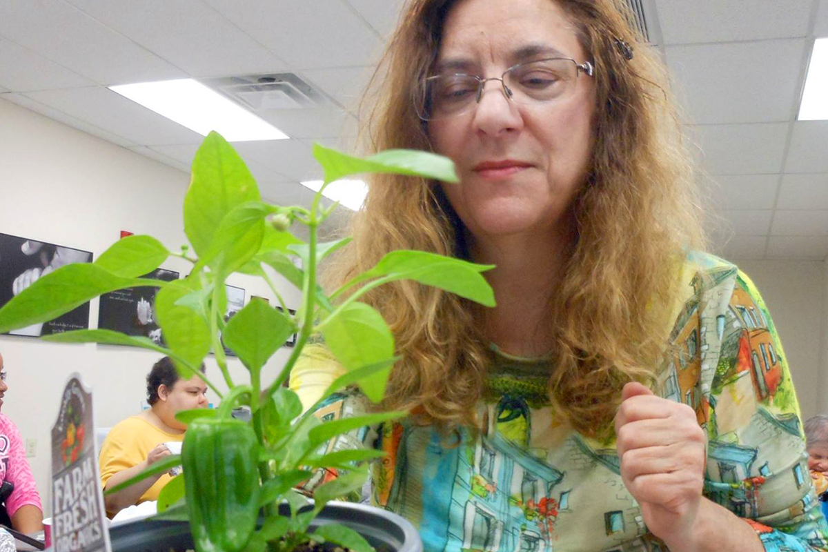Photo of a client as she tends to a plant that she potted
