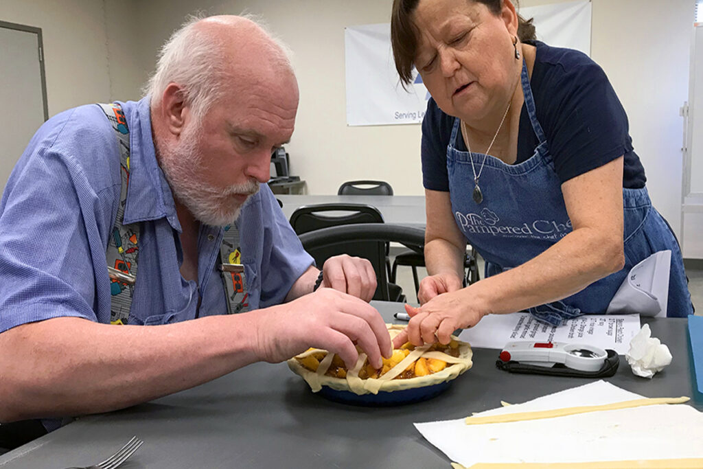 An instructor teaching a client how to make a pie