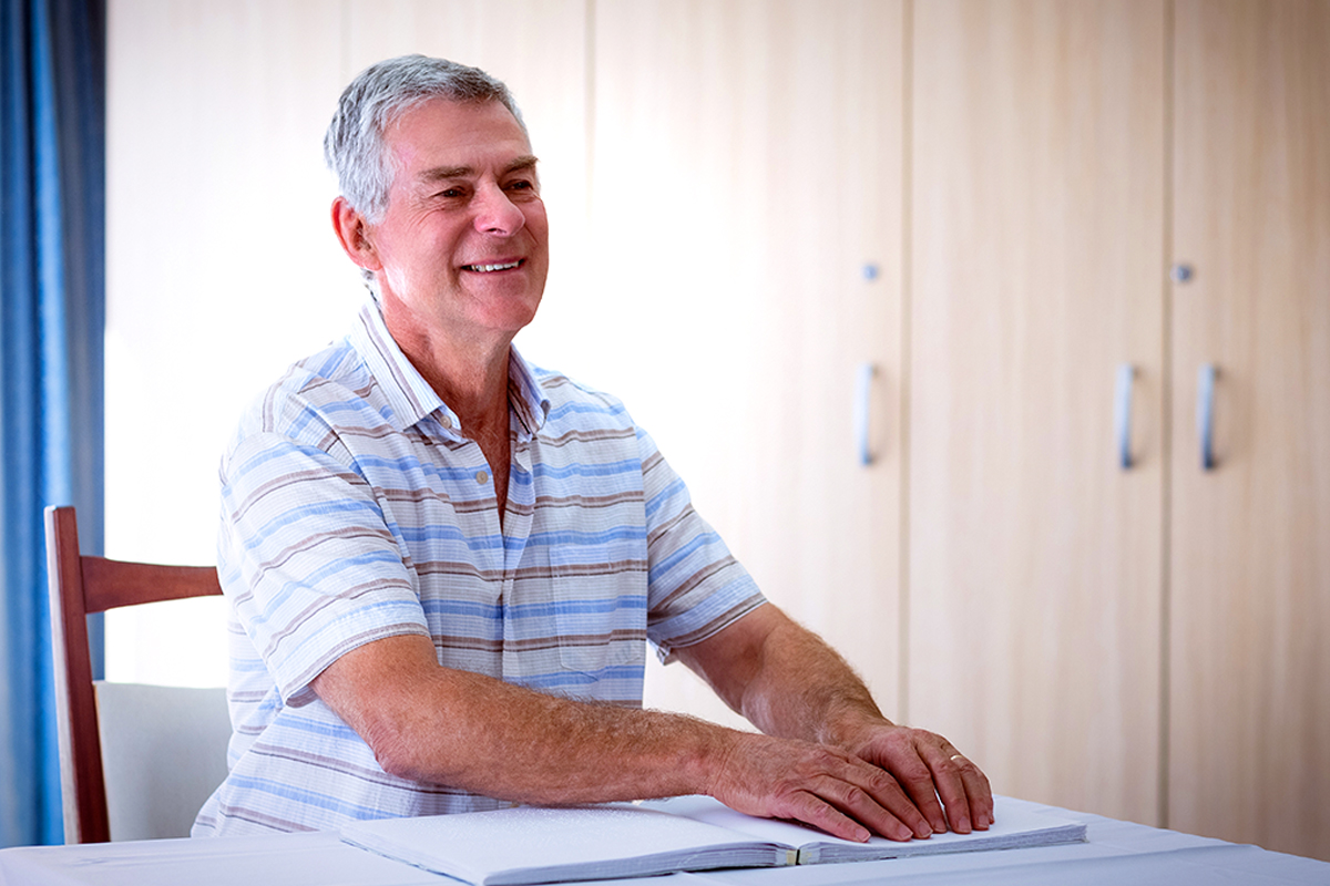 Picture of an older gentlemen reading from a Braille book