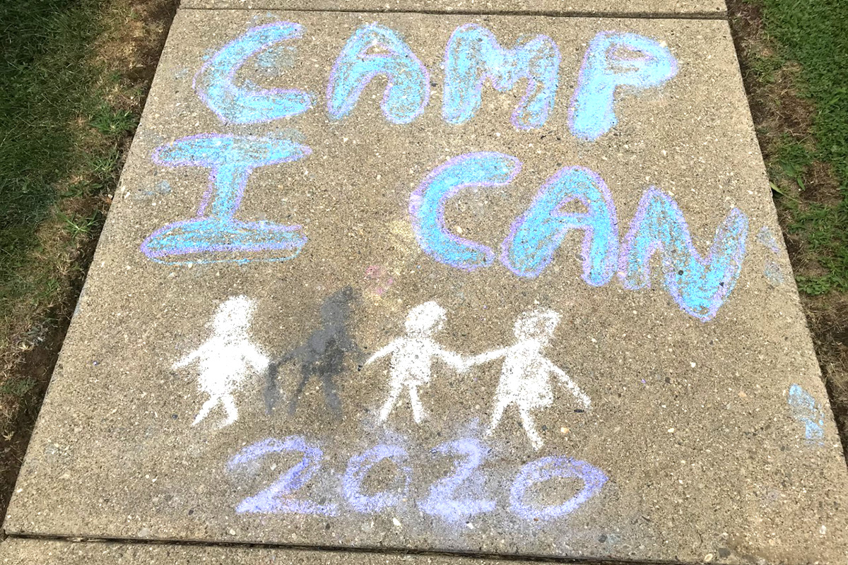 A chalk drawing of the Camp I CAN! 2020 graphic on a sidewalk panel