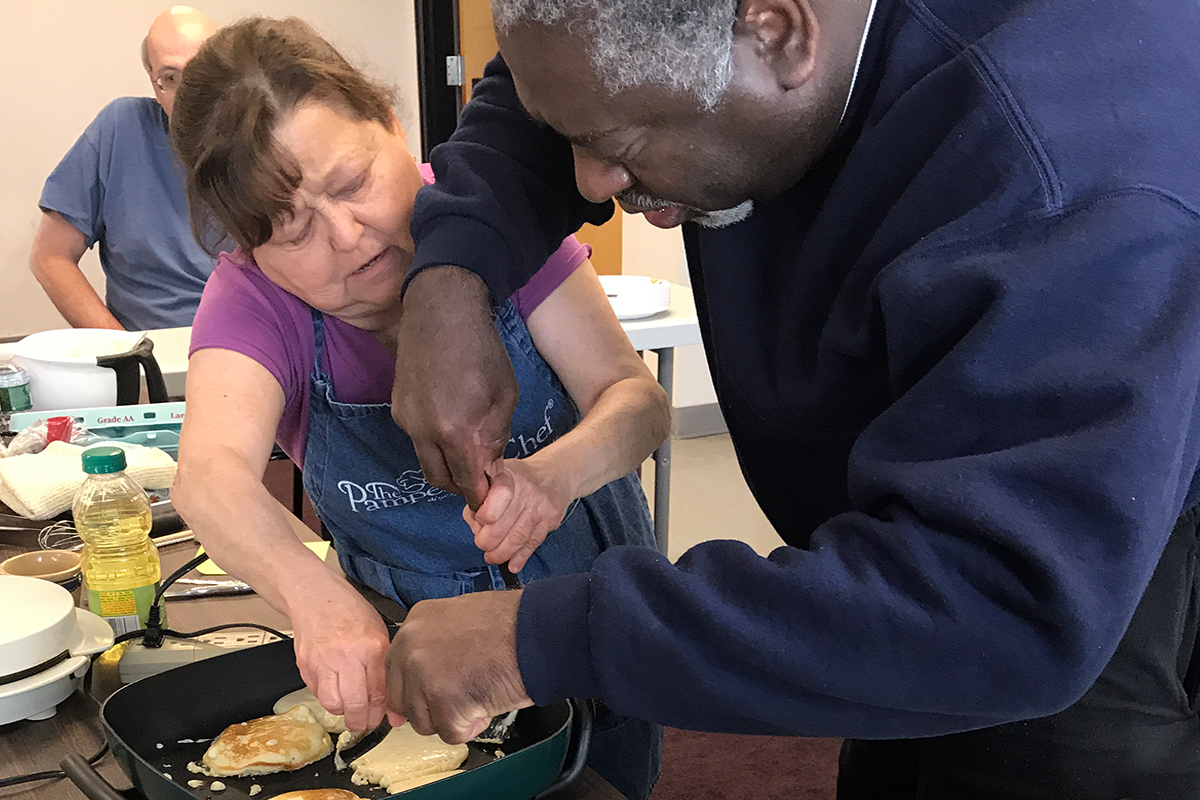 Photo of two people making pancakes during a previous breakfast cooking class