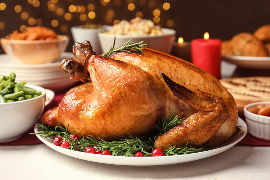 A baked turkey on a dining table along with bowls of side dishes