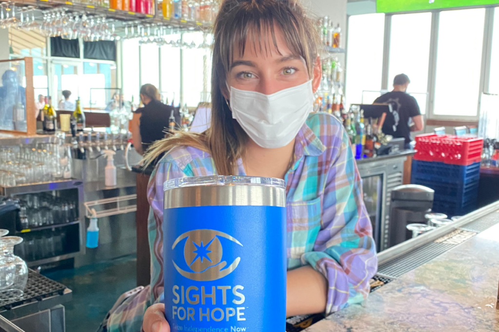 Photo of a woman holding a blue YETI tumbler branded with the Sights for Hope logo