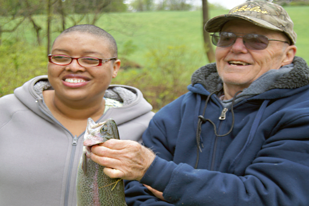 Photo of a Lions Club member and a client showing off a fish that they caught