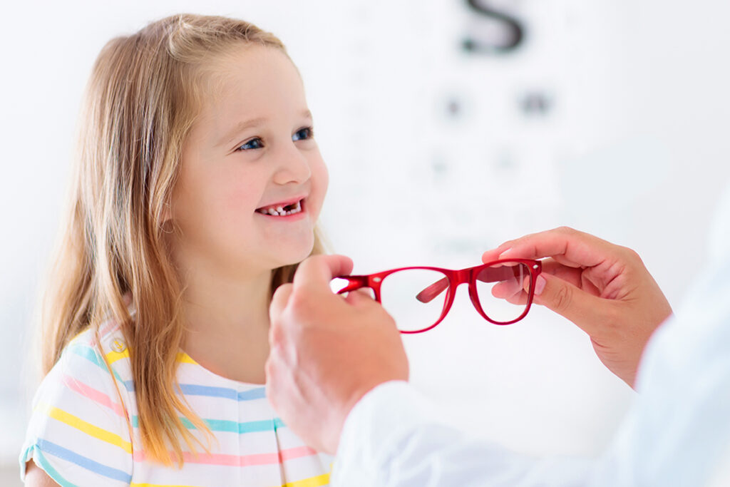 Image of a pre-kindergarten girl being fitted for glasses by an eyecare professional
