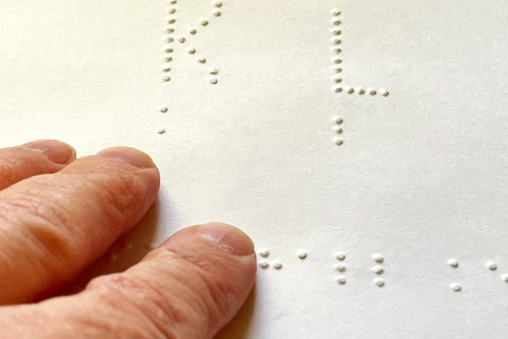 Photo of fingers running over text in Braille