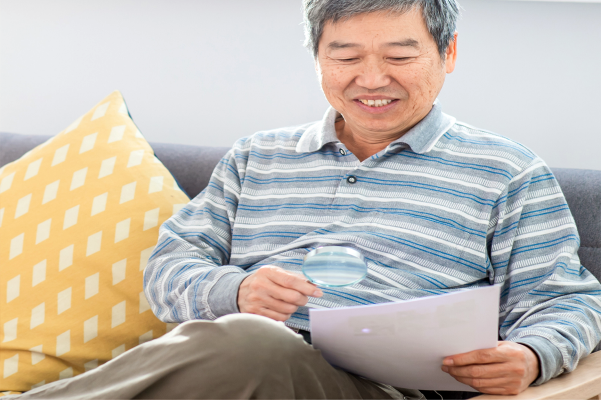 Photo of a man using a magnifer to read a piece of paper