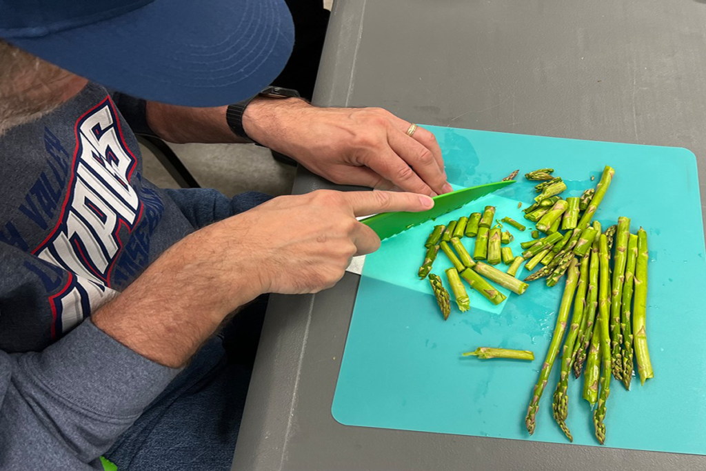 Photo of a Sights for Hope client cutting asparagus during a cooking class