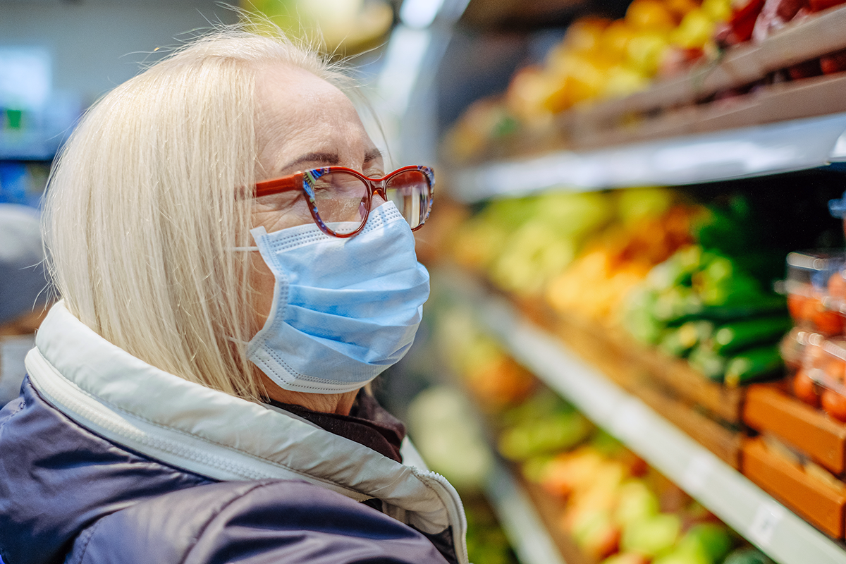 An older woman with glasses in a grocery store while wearing a face mask