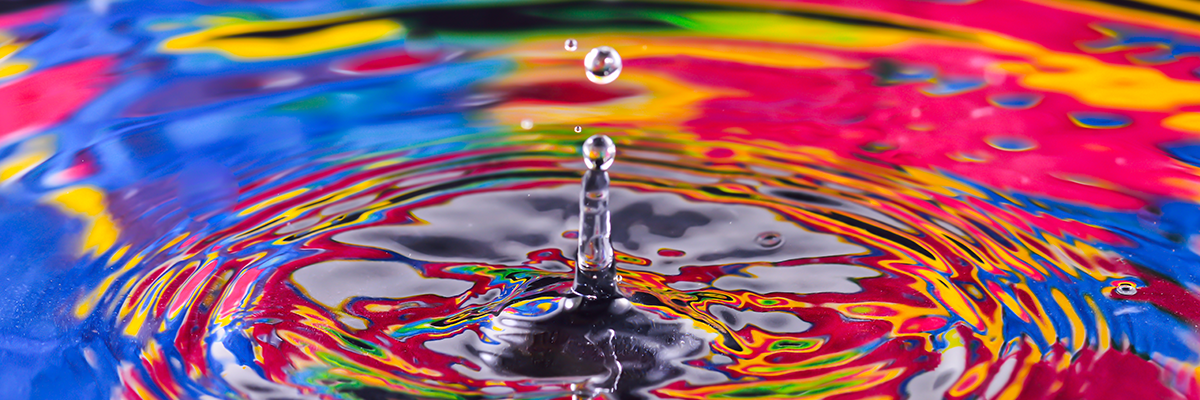 Picture of a water drop splashing into water reflecting vibrant colors