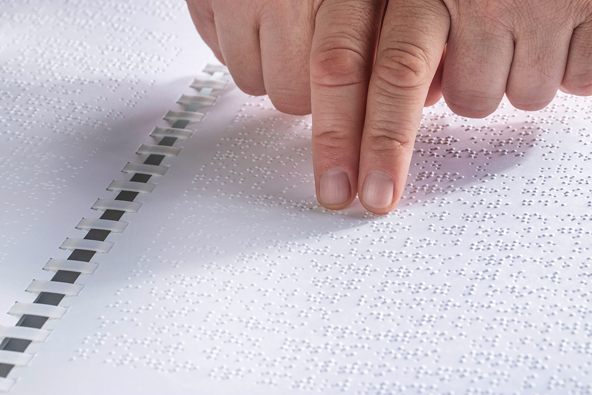 Photo of a person using two hands to read Braille