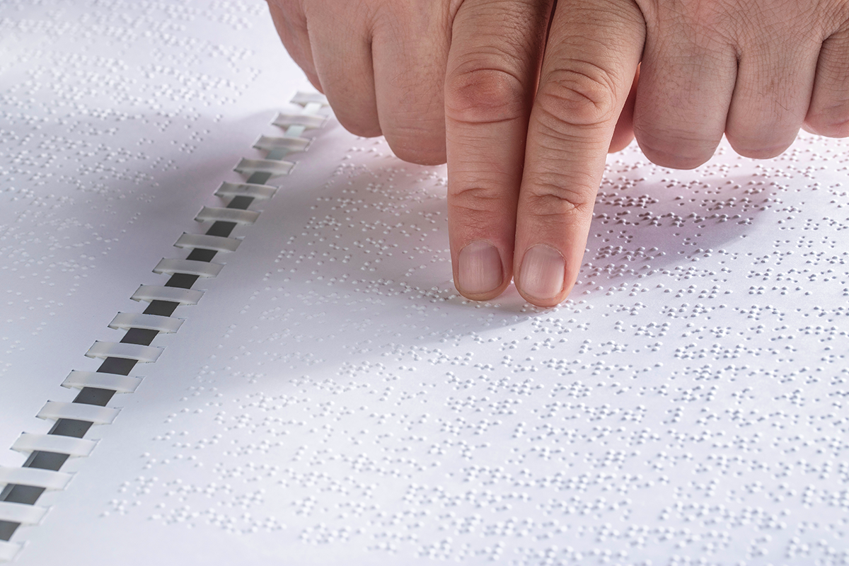 A person using two hands to read Braille