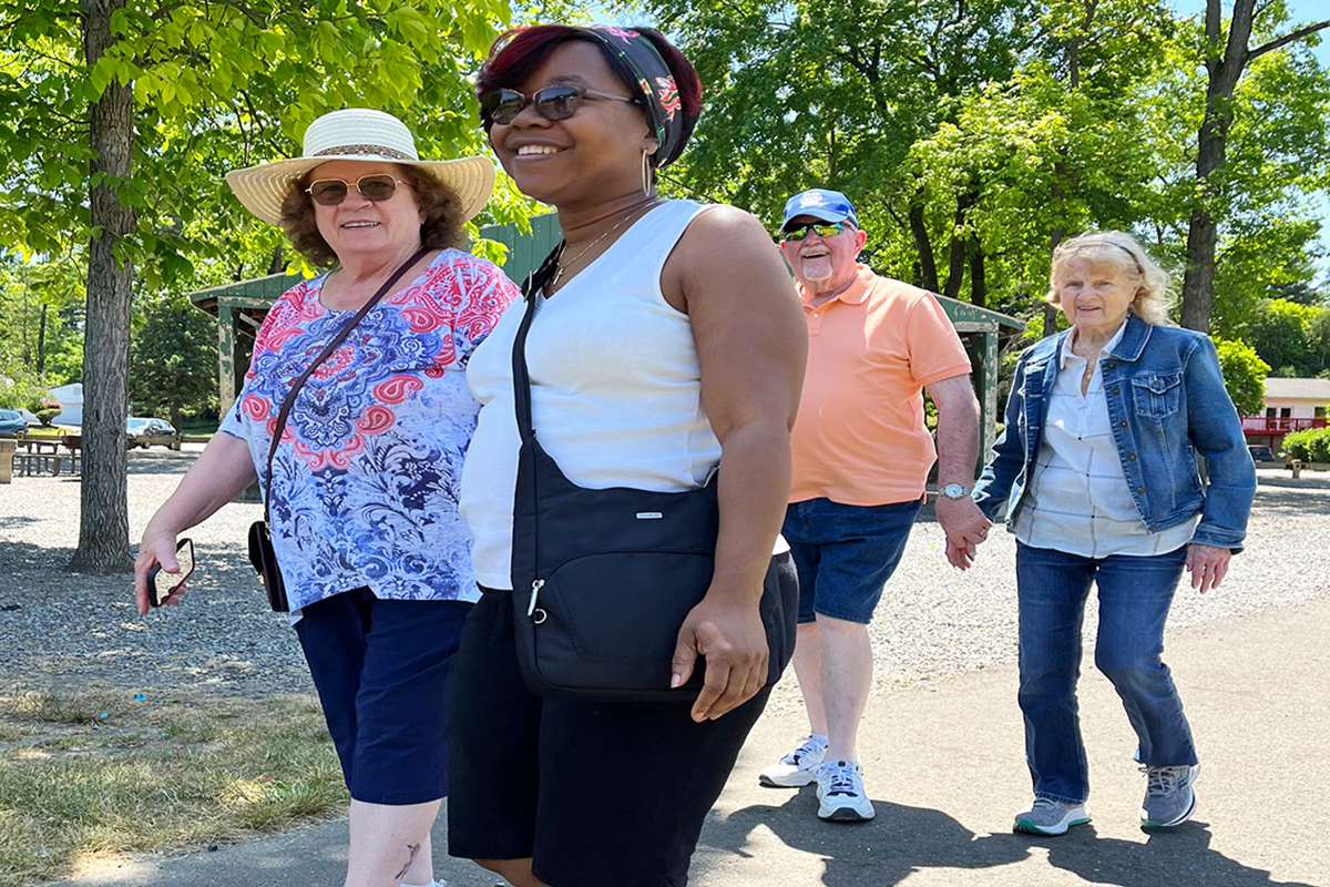 Three Sights for Hope clients and one volunteer walking in a park with smiles on their faces