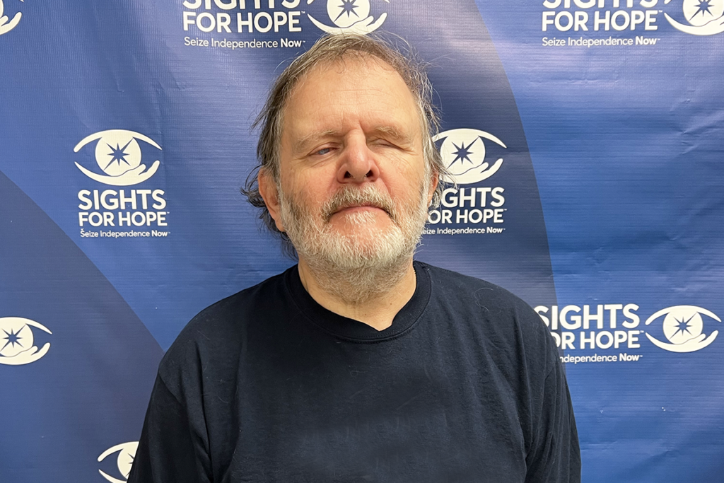 Photo of Gary Dvorshak in front of a blue Sights for Hope step-and-repeat banner