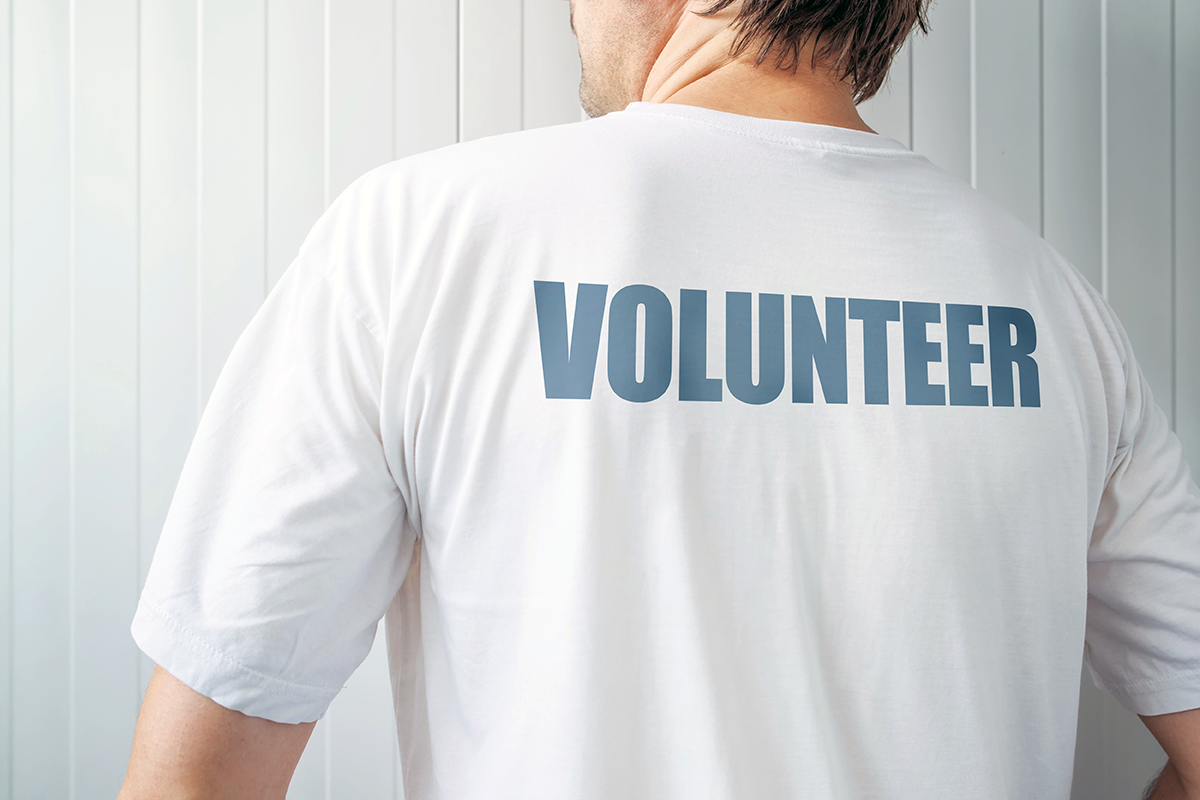 The back of an adult male's white shirt with the word "Volunteer" written upon it