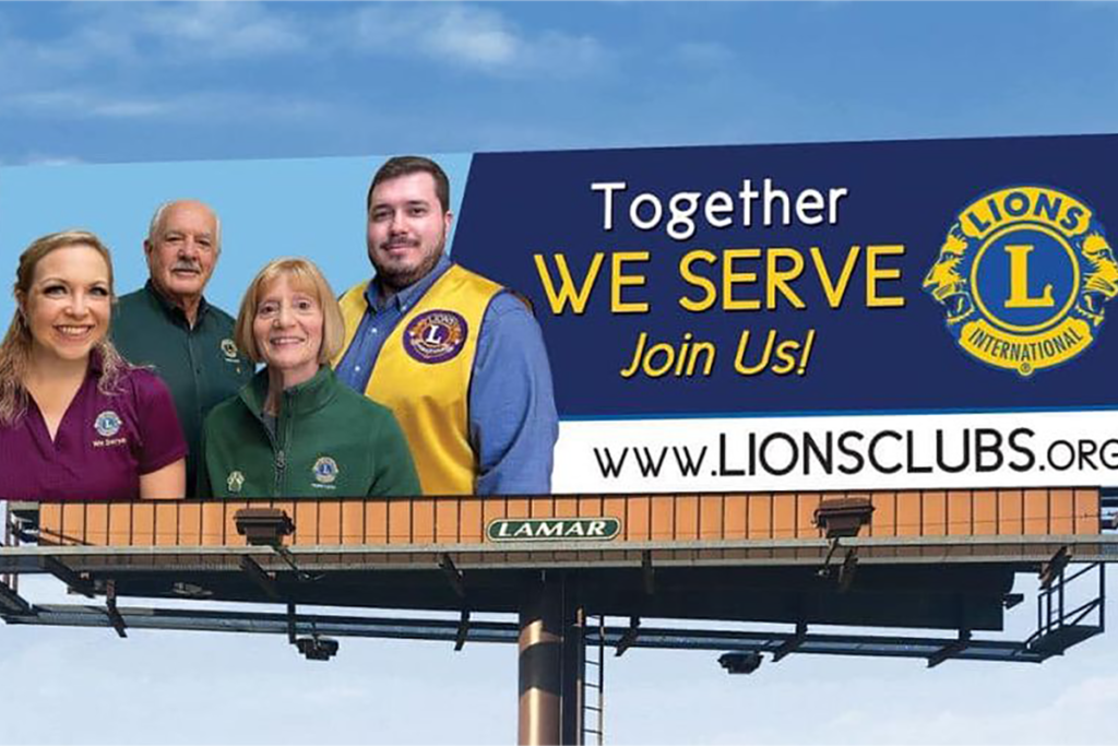 Billboard featuring four people in Lions Club attire smiling under a blue sky. Text reads, "Together We Serve. Join Us!" with www.lionsclubs.org.