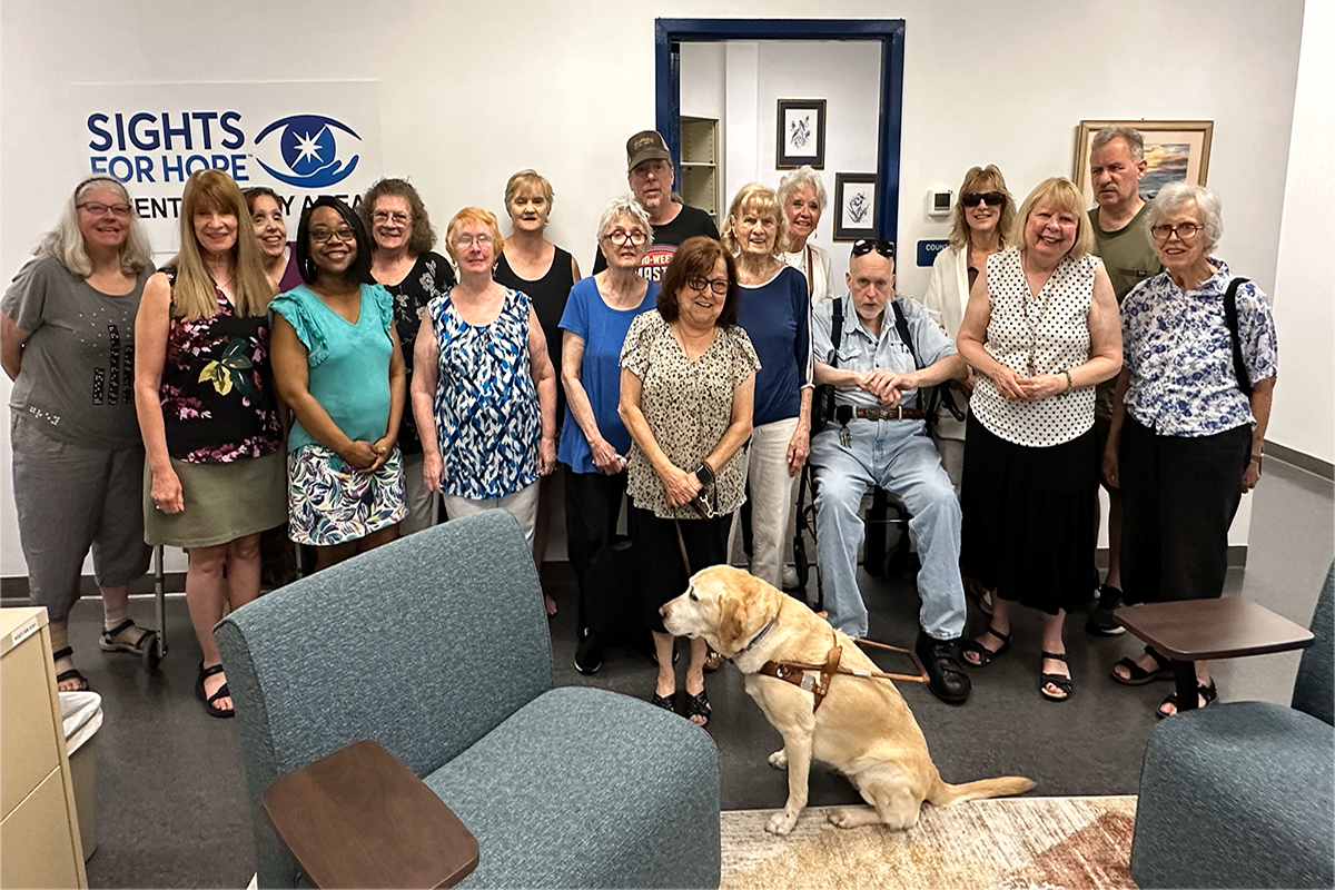 Approximately 15 Sights for Hope clients and a service dog pose inside Sights for Hope's new Client Activity Area at its Lehigh Valley Services Center