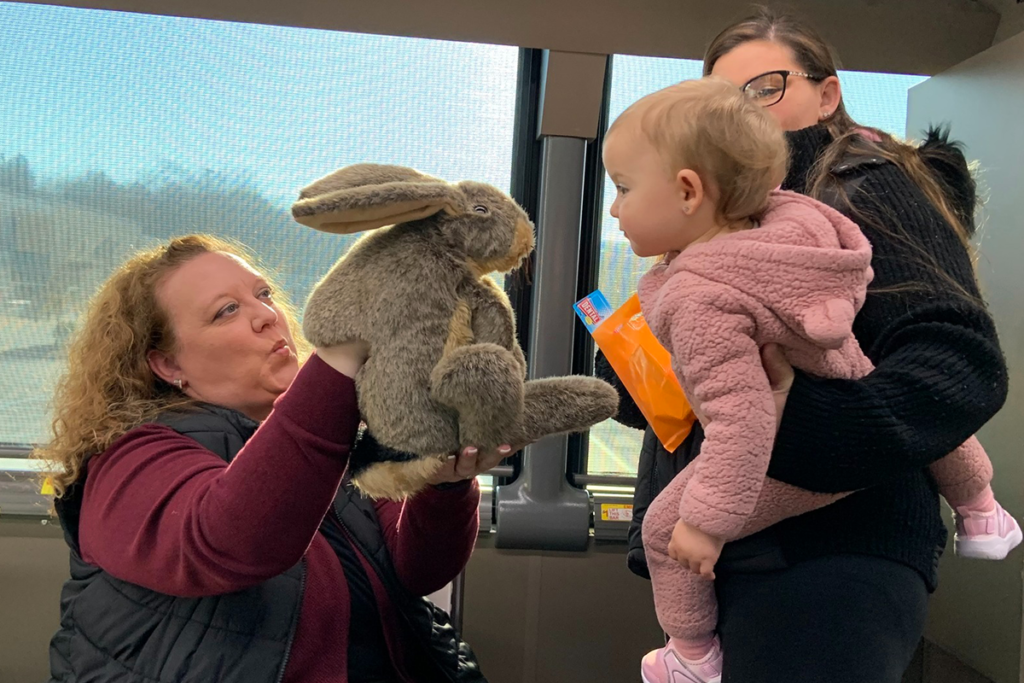 A toddler looks at a stuffed C. Well Bunny character held by a Sights for Hope Prevention Specialist