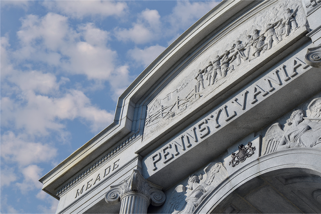 Stone archway with “Pennsylvania” inscribed, featuring carved figures and columns. The sky above is blue with scattered clouds, evoking a majestic tone.