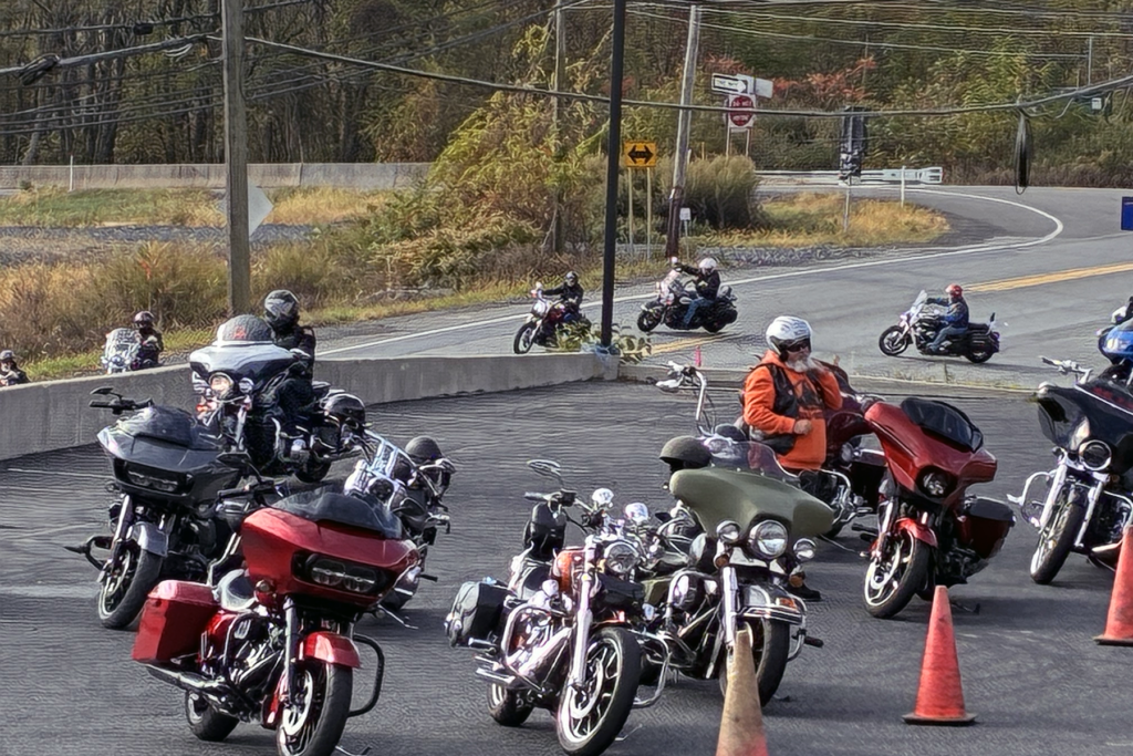 A group of motorcyclists start the Bikers for Sight run while other riders prepare to begin. Riders, wearing helmets and gear, create a lively atmosphere.