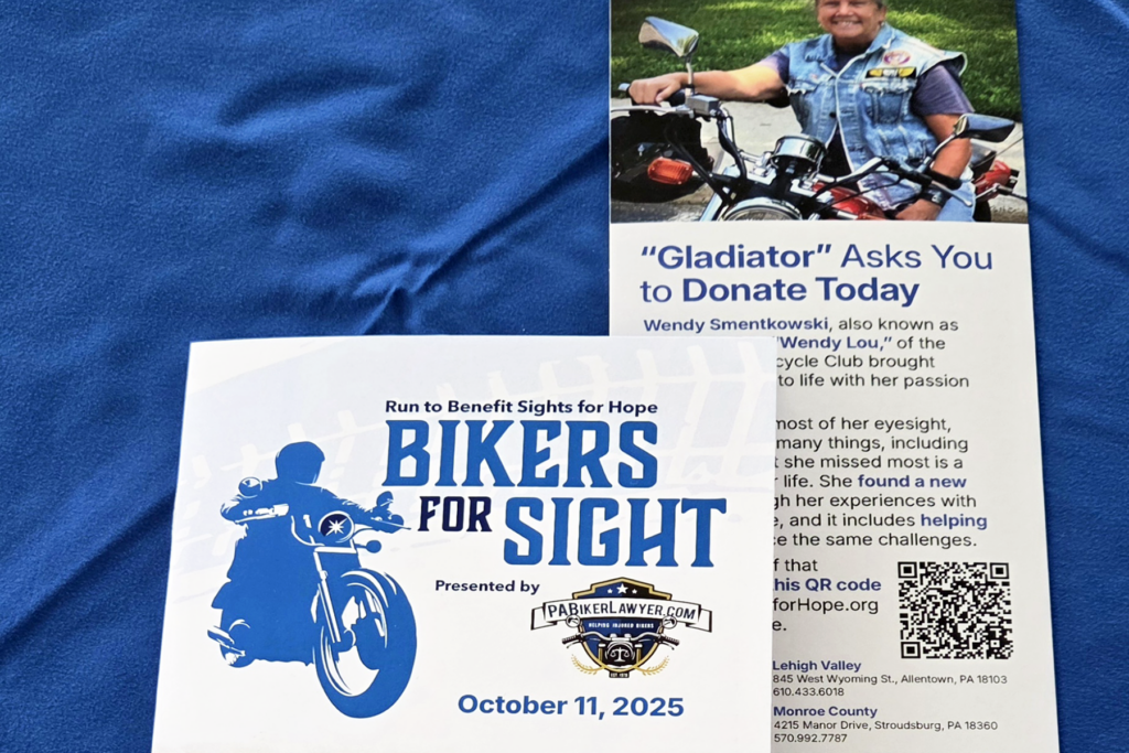 Event program and rack card for the Bikers for Sight event on a blue tablecloth.
