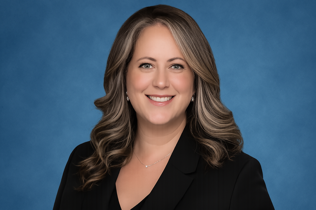 Kate Raymond shown with a black blazer against a blue background.