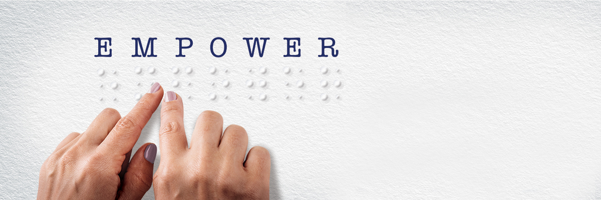 Two hands feeling letters in Braille that spell out the word EMPOWER