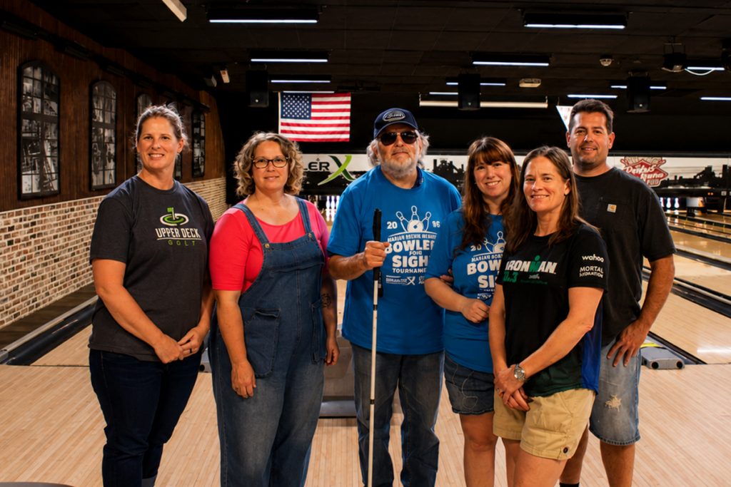 Six participants pose on a bowling lane during the 2026 Marian Boehm Memorial Bowlers for Sight Tournament, including a Sights for Hope client holding a white cane.