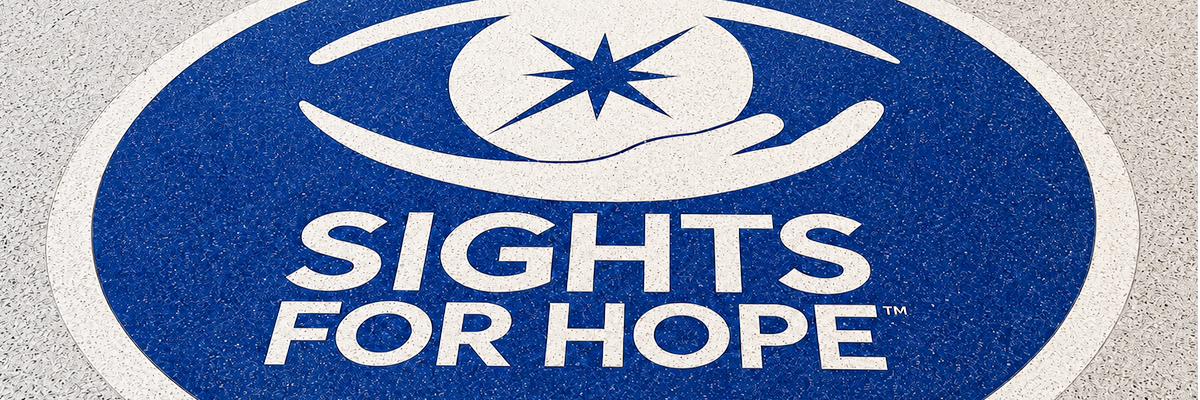 A white Sights for Hope logo inside a dark blue circular mark that is set against a textured gray floor.