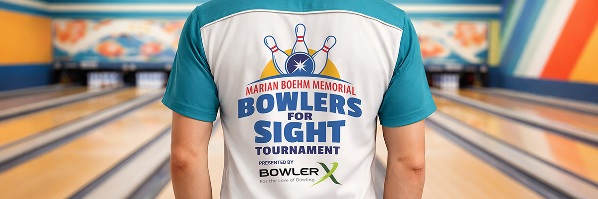 A person wearing an aqua blue and white bowling shirt stands in a bowling alley. The back of the shirt shows a logo that reads "Marian Boehm Memorial Bowlers for Sight Tournament. Presented by BowlerX."